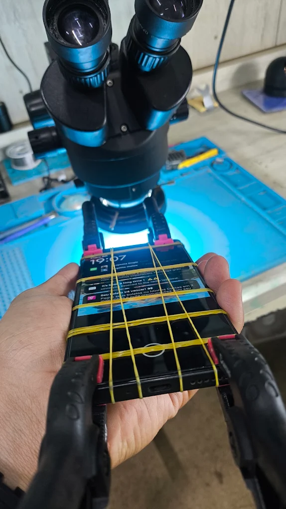 Técnico reparando smartphone no microscópio